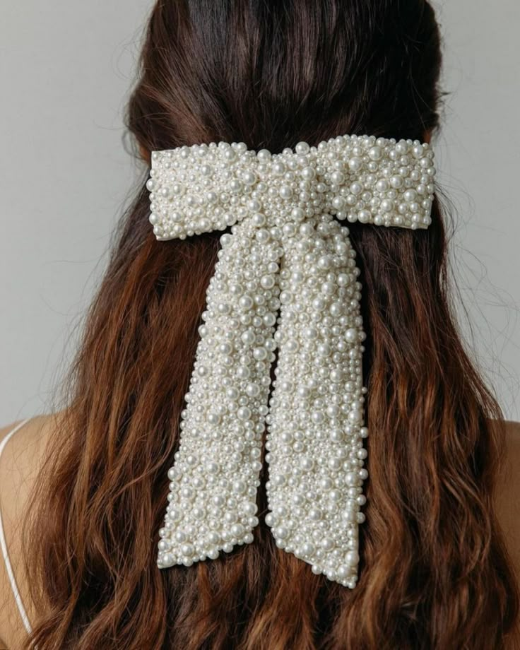 the back of a woman's head wearing a white bow with pearls on it