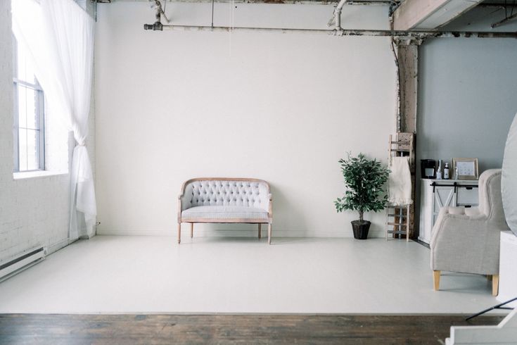 an empty room with a couch, chair and potted plant