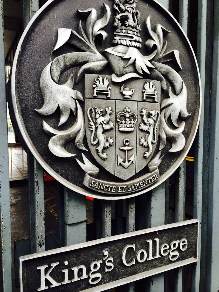 the king's college sign is attached to a metal gate in front of a building