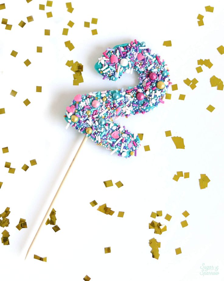 a cake on a stick with sprinkles and confetti around it