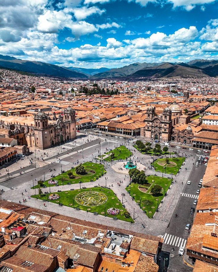 an aerial view of a city with lots of buildings and green grass in the middle