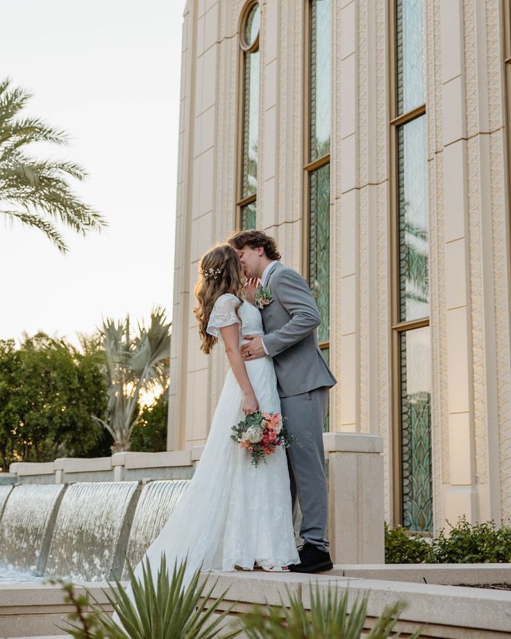 a bride and groom kissing in front of a building