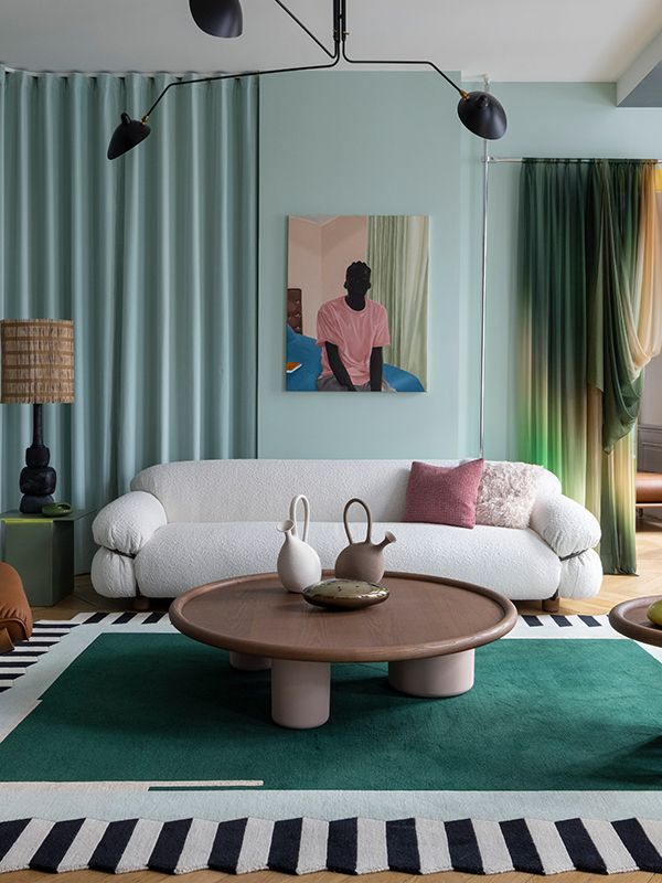 a living room with a white couch and green rugs on the floor next to a coffee table