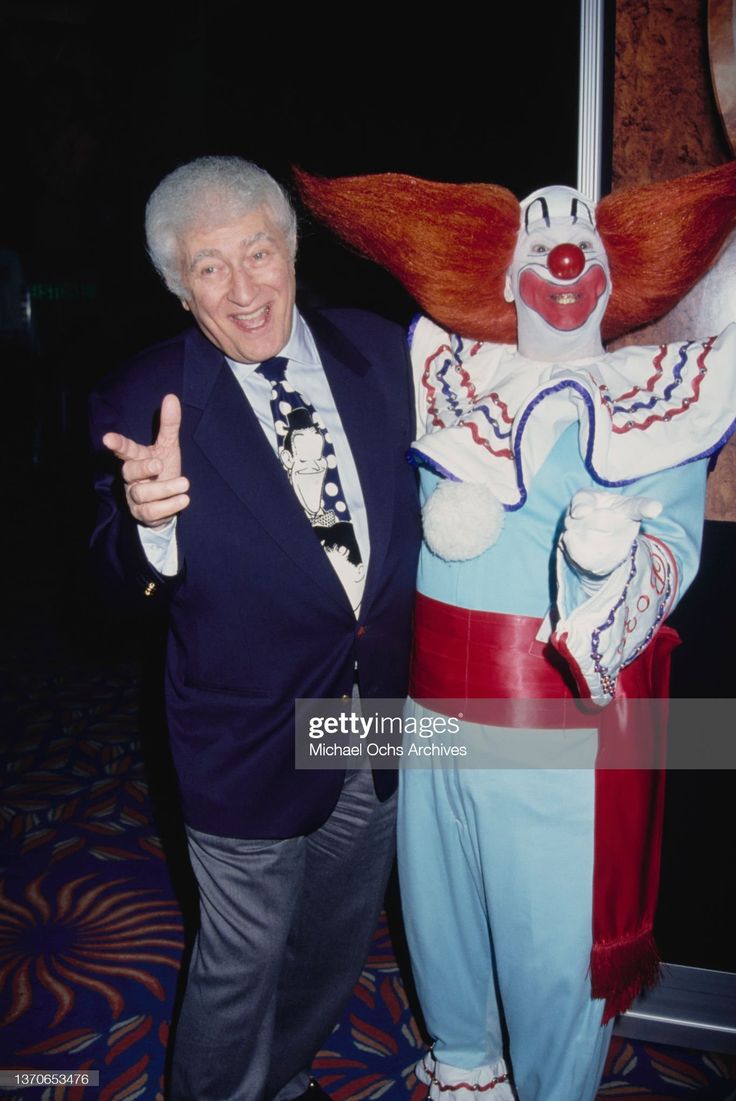 an older man standing next to a clown statue