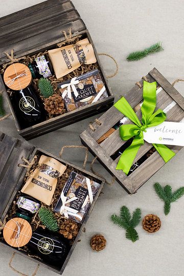 three wooden boxes filled with assorted items on top of a white surface next to pine cones