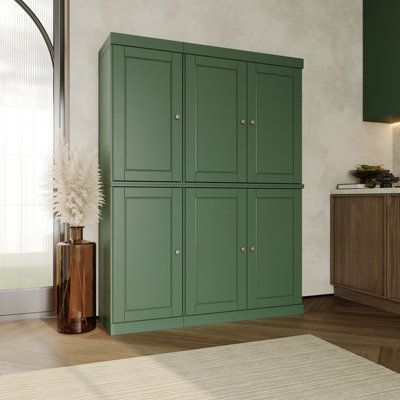 a kitchen with green cupboards and white rug on the floor in front of it