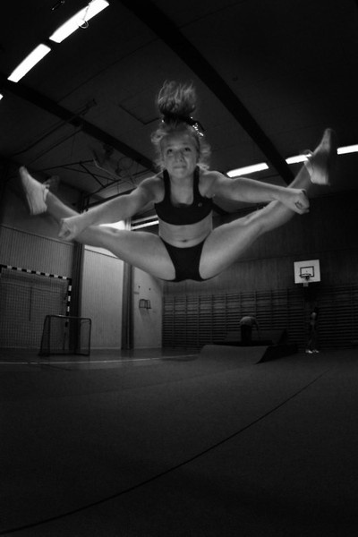 a woman in a black and white photo doing a handstand on a basketball court