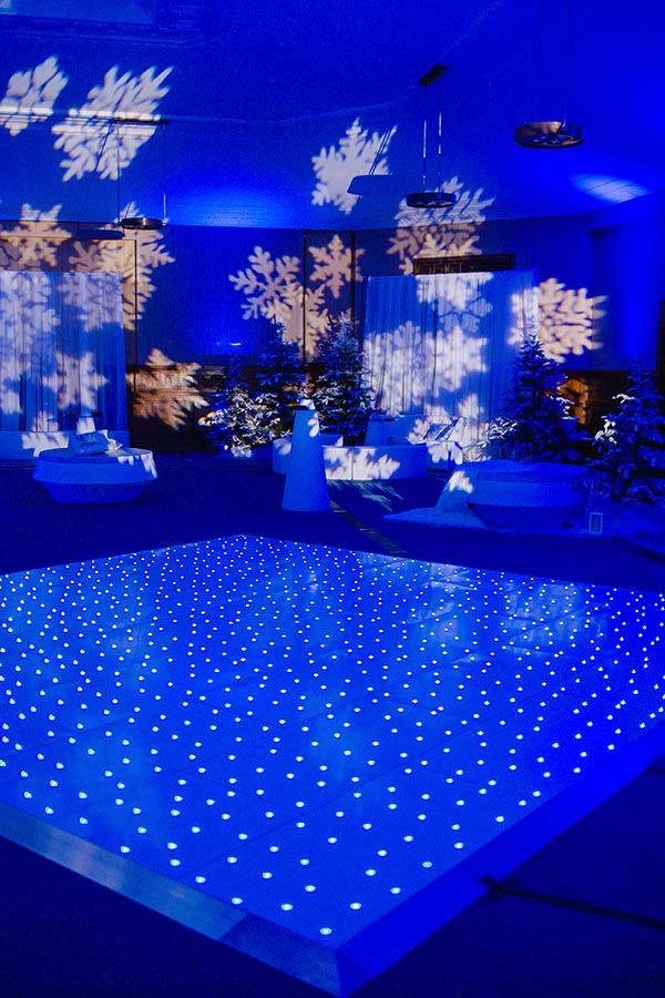 an illuminated dance floor with snowflakes on it and blue lights in the background