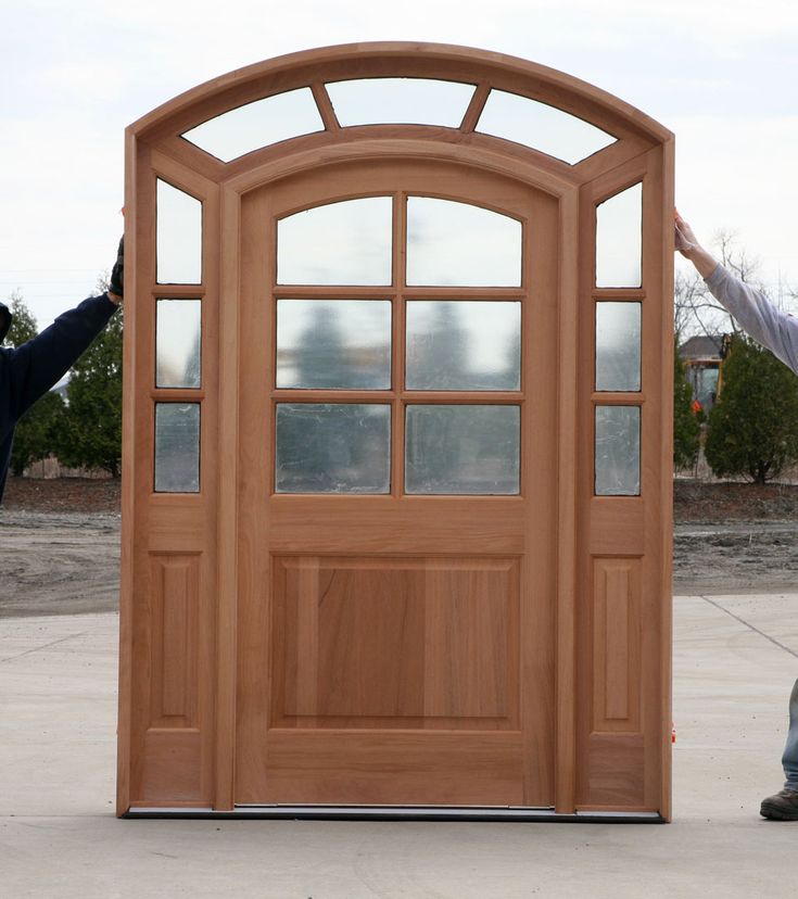 a man standing in front of a wooden door with glass panes on the side