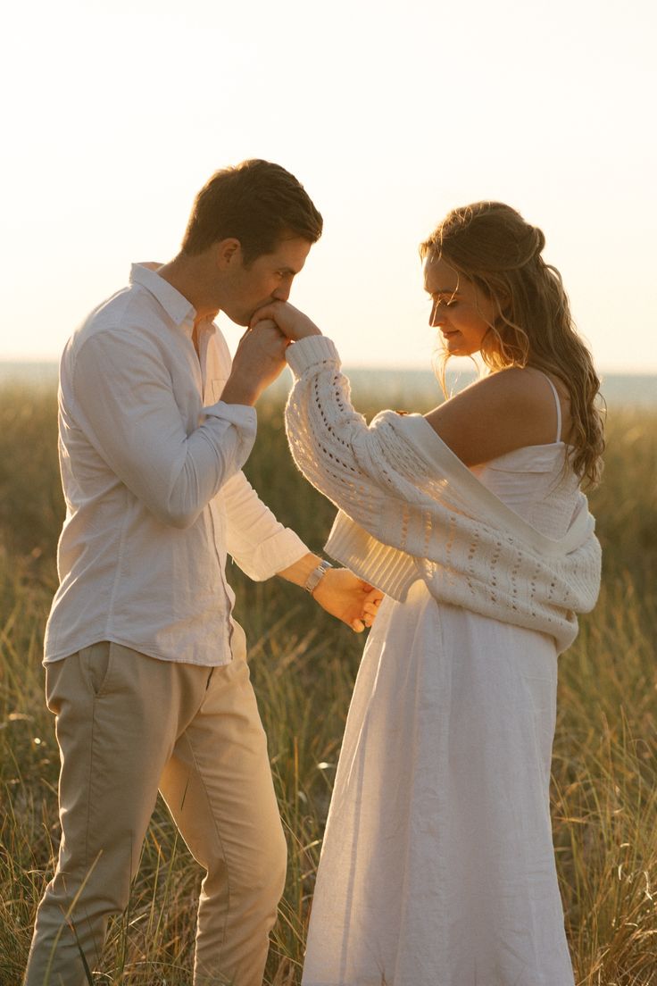 a man and woman standing next to each other in tall grass