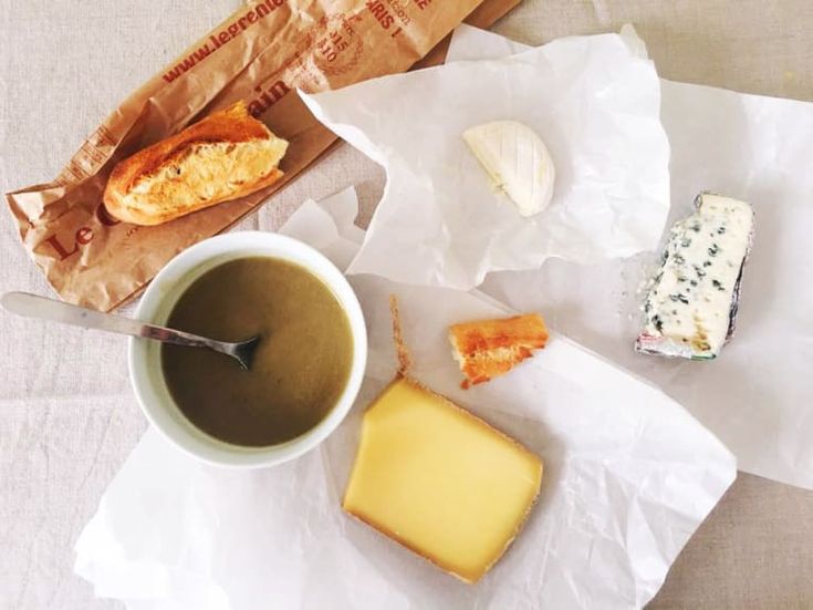 a cup of coffee and some food on a white tablecloth with brown paper bags