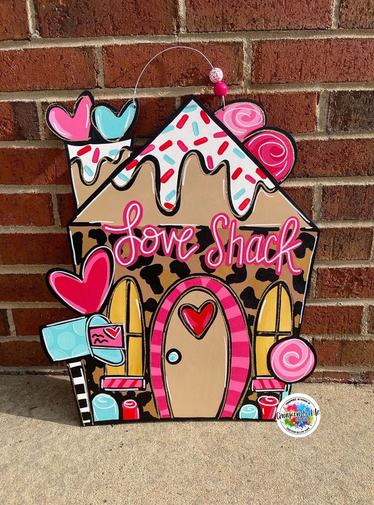 a wooden sign that says love shack on the side of a brick wall with an image of a house