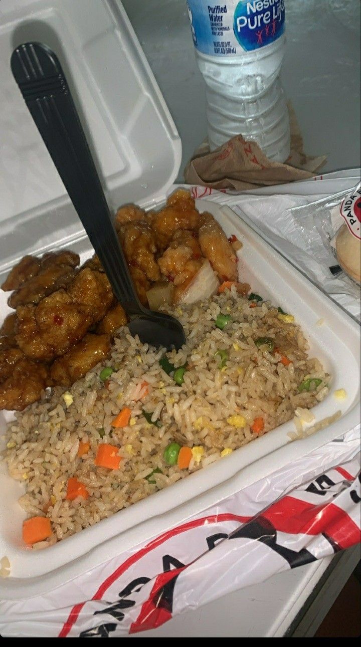 a plastic container filled with rice, chicken and veggies next to a water bottle