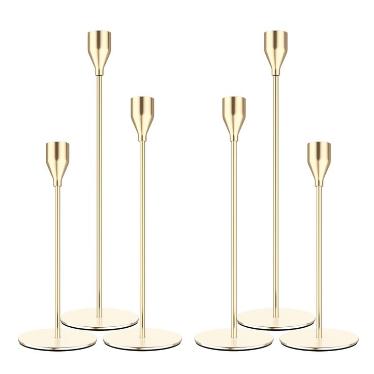 three gold metal candlesticks on white bases