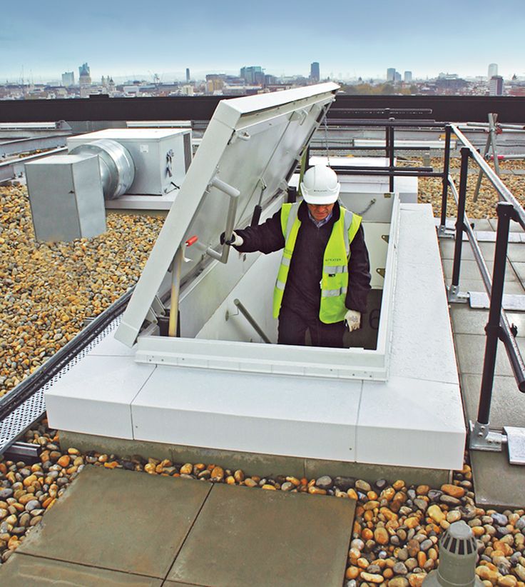 a man in safety vest standing on top of a roof