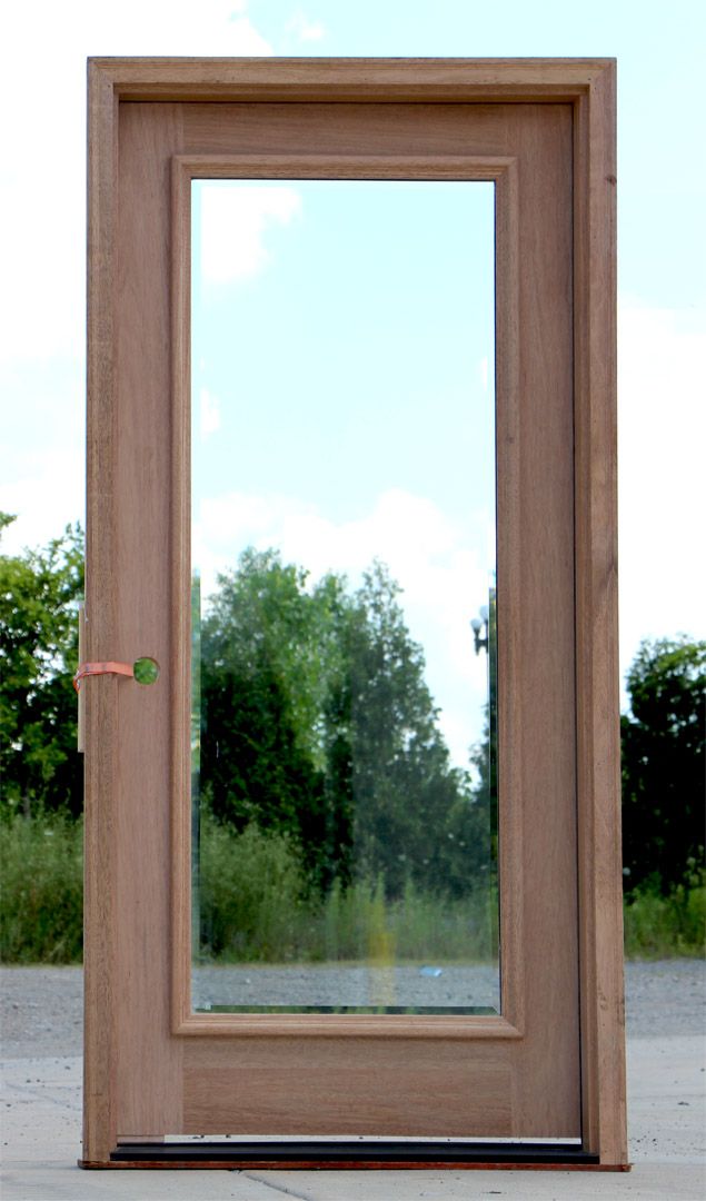 a wooden door with a mirror on the side and trees in the backround