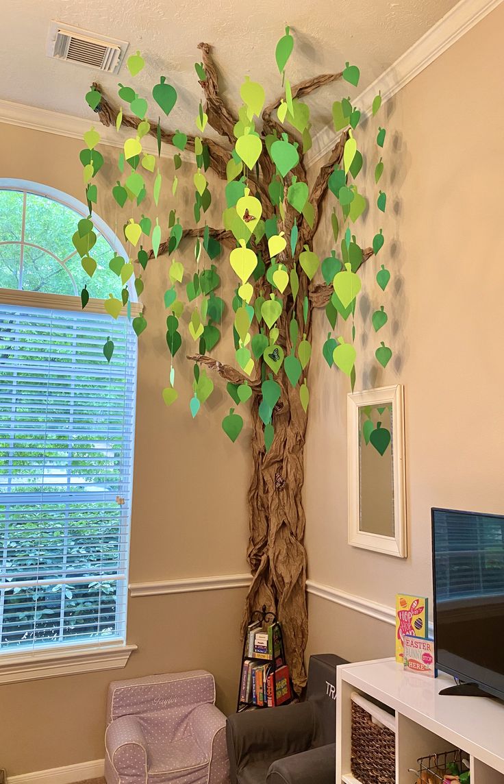 a living room with a tree made out of paper and some pictures on the wall