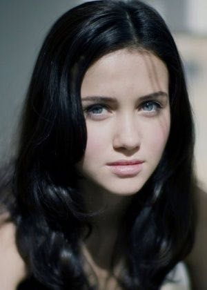 a black and white photo of a woman with long dark hair looking at the camera