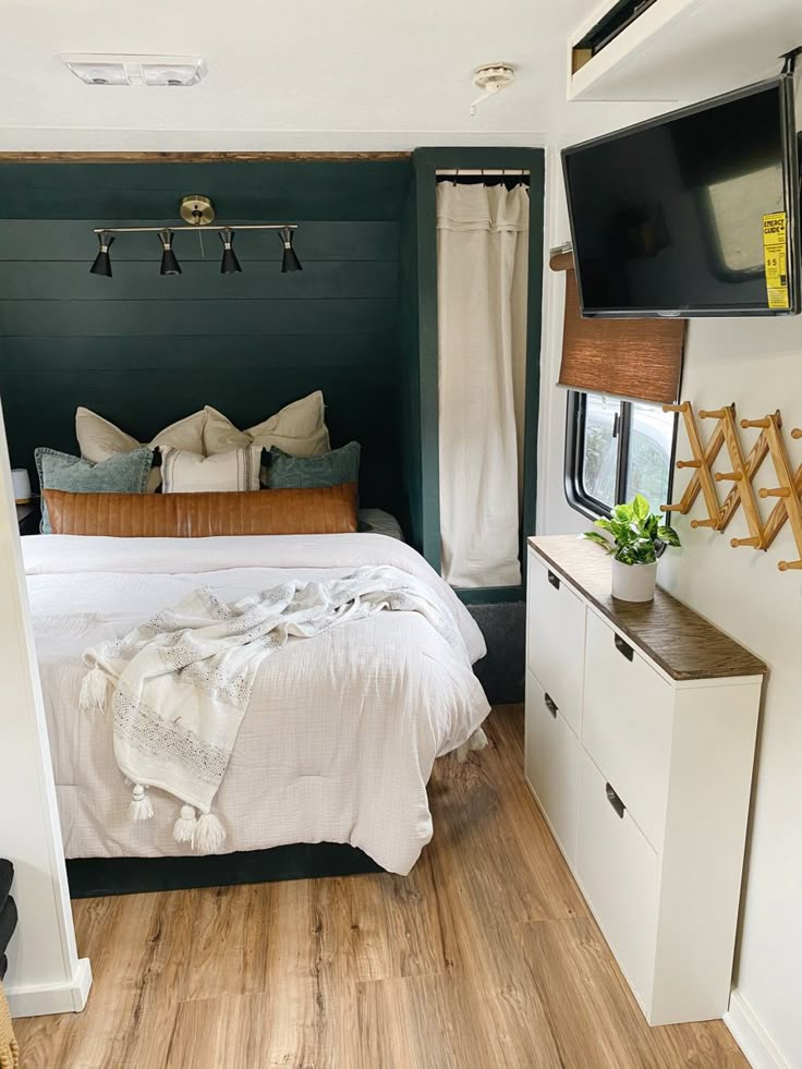 a bedroom with a bed, dressers and television in the wall next to it