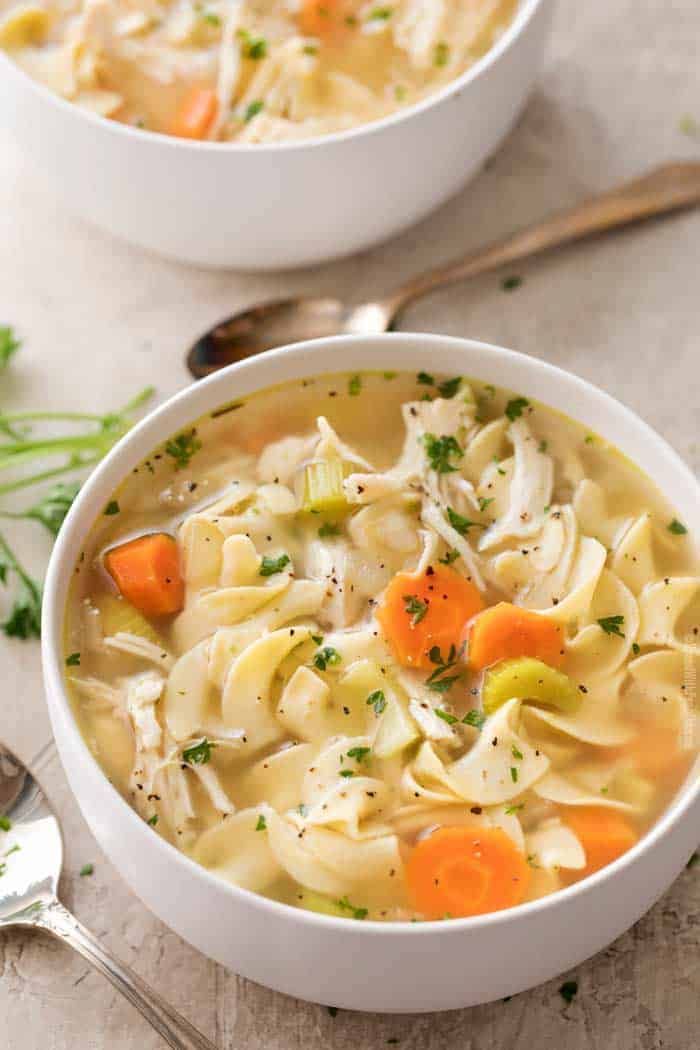 two bowls of chicken noodle soup on a table