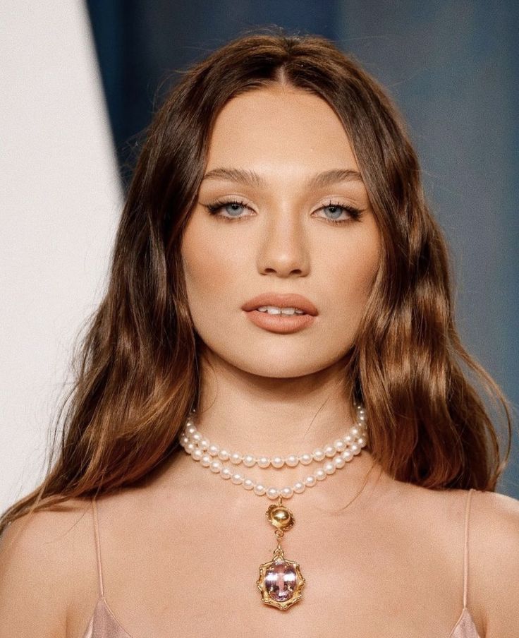 a woman with long hair wearing pearls and a necklace