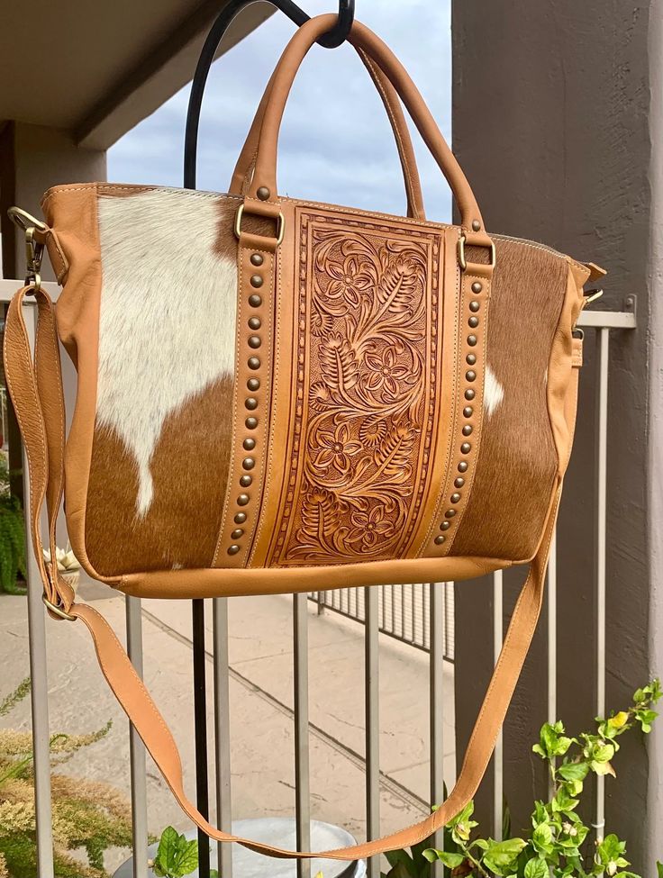 Gorgeous Tooled Leather tote or briefcase -  Texas sized The leather is very soft and luxurious. This tote is perfect to be used as a travel tote, diaper bag, work bag, big ole purse, weekender bag, crossbody purse... so many uses!! Main compartment holds your iPad, laptop, keys, wallet, phone, makeup bag, etc. Zippered closure Inside: - zippered pocket - 2 open pockets inside - leather handle, side and back - removable plain leather crossbody strap - these are one of a kind and cowhide will be different on every purse as no 2 are alike. 17" x 11.5" x 4" On-the-go Tote Briefcase With Detachable Handle, Leather Rectangular Diaper Bag For On-the-go, Brown Weekender Bag With Detachable Handle For Travel, Brown Weekender Bag With Detachable Handle, Brown Tote Diaper Bag For Daily Use, Brown Diaper Bag With Double Handle For Daily Use, Brown Travel Bag For On-the-go, Leather Travel Bag With Top Carry Handle, Leather Travel Bag Tote With Top Carry Handle