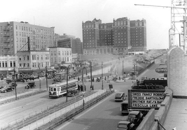 an old black and white photo of a city street with cars, buses and buildings