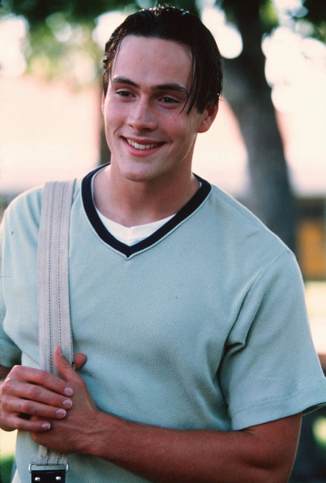 a young man is smiling and holding his cell phone