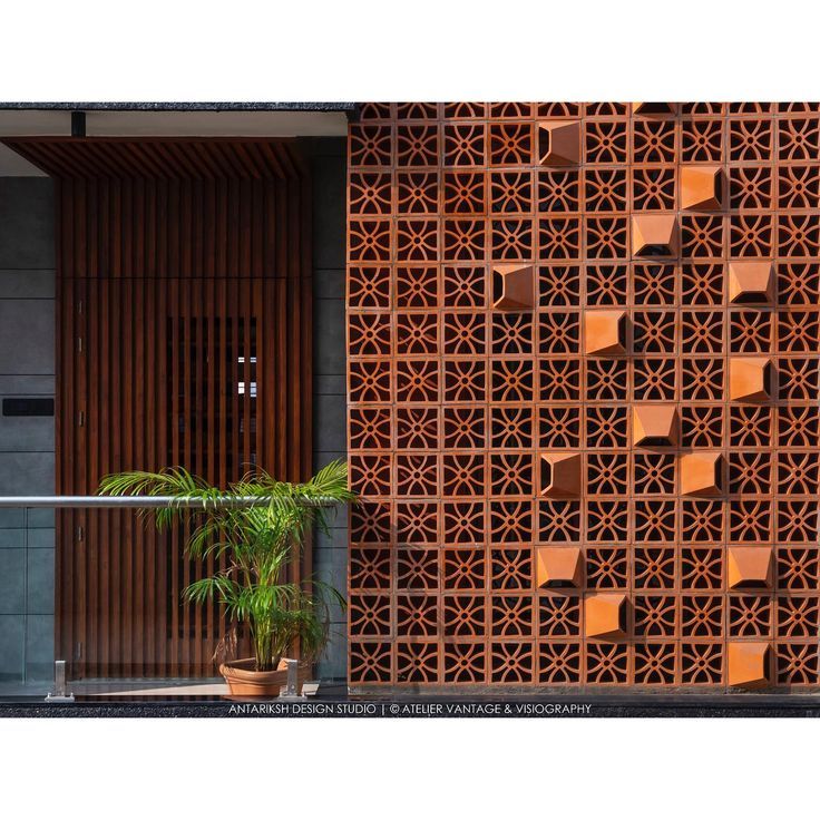 a plant in front of a wooden wall with geometric designs on it's sides