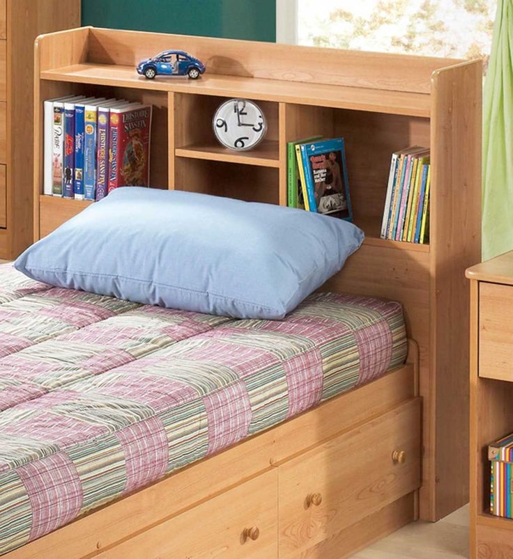 a child's bed with bookshelf and pillows