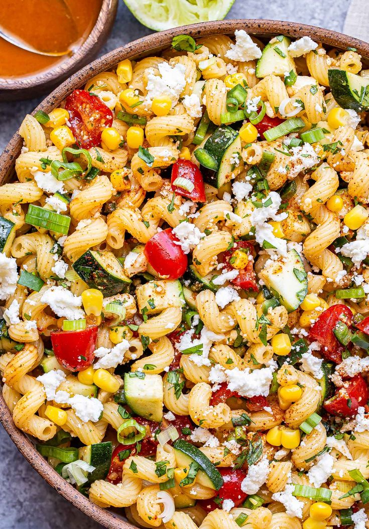 a bowl full of pasta salad with feta cheese and tomatoes