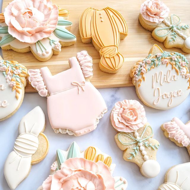 cookies decorated with pink and white icing are on a tray next to some flowers