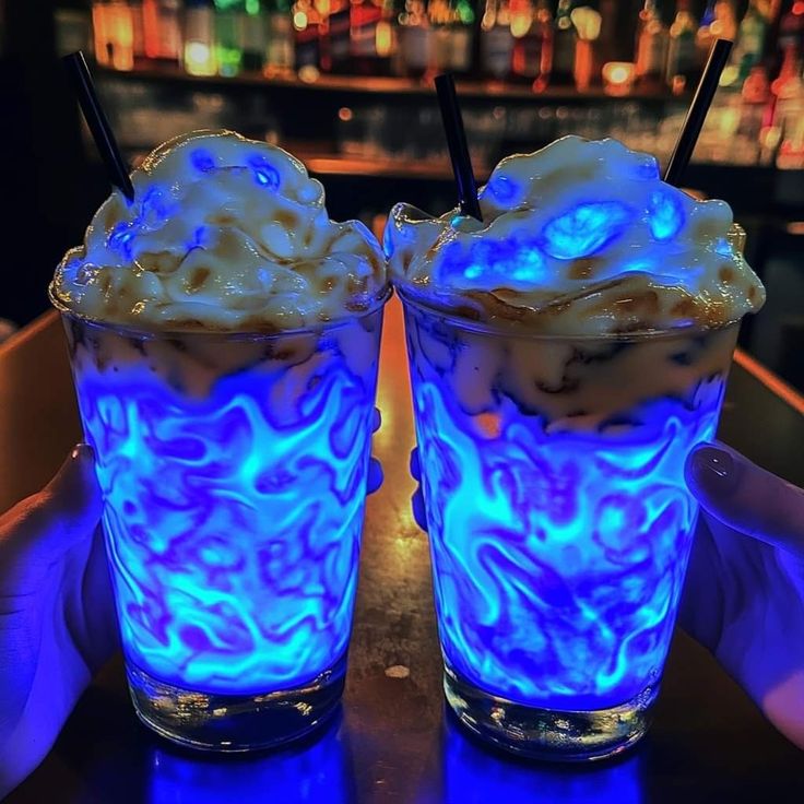 two glasses with ice cream in them sitting on a table next to a neon bar