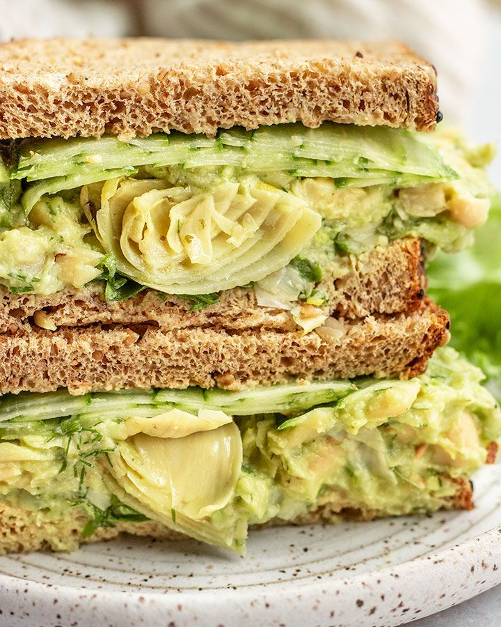 a sandwich with avocado and lettuce is stacked on top of each other