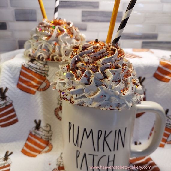 two mugs filled with whipped cream and topped with pumpkin patch frosting, sprinkled with candy canes