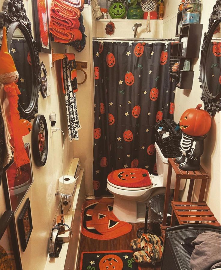 a bathroom decorated for halloween with pumpkins and decorations on the shower curtain, toilet seat cover and rug