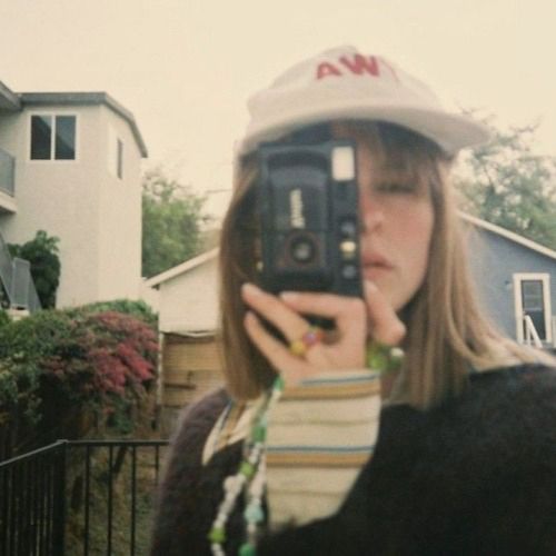 a woman is taking a selfie with her cell phone in front of some houses