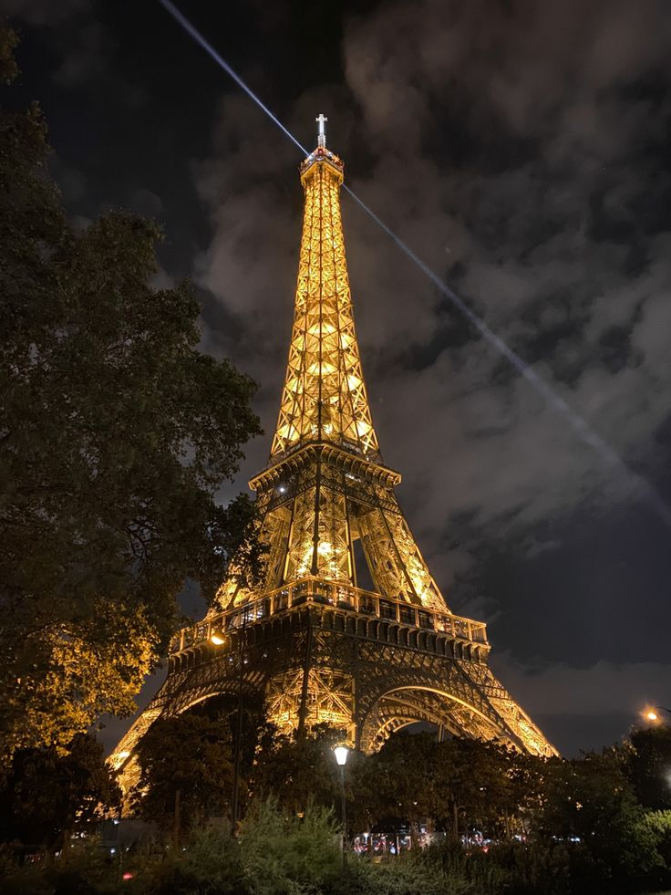 the eiffel tower lit up at night with lights on it's sides