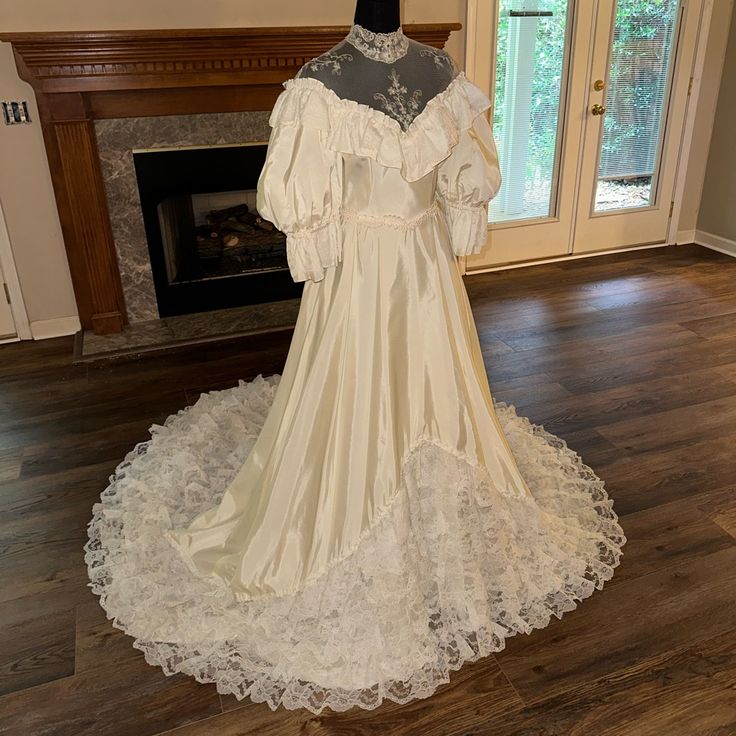 an old fashioned wedding gown on display in front of a fire place with a fireplace