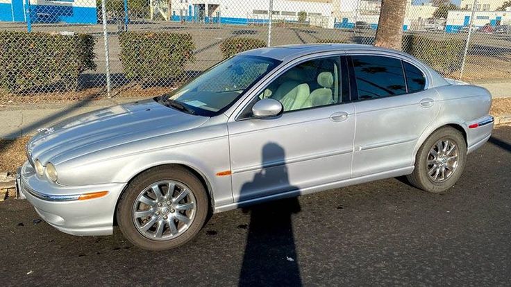 a silver car parked in front of a chain link fence