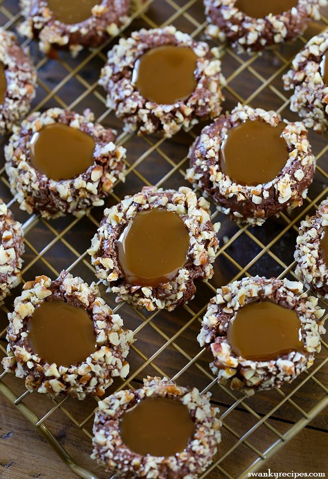 chocolate covered cookies on a cooling rack with peanut butter in the middle and chopped nuts around them