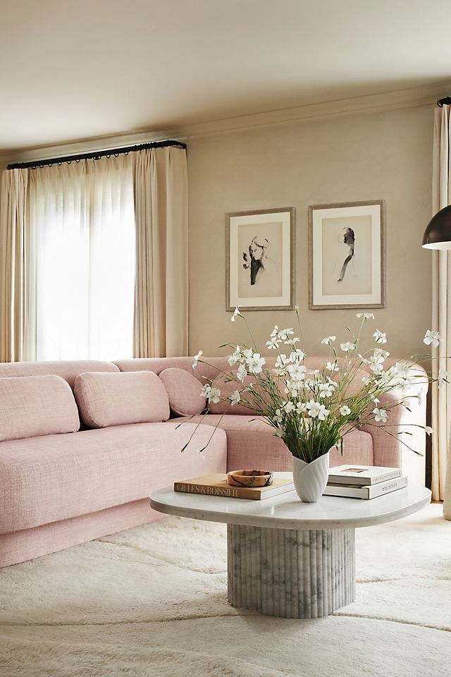 a living room with pink couches and white flowers in the vase on the coffee table