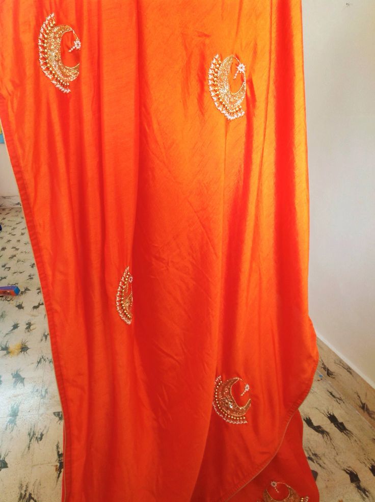 "Stunning orange semi silk saree with intricate all over chaandbali design hand embroidery and rawsilk tissue offwhite unstiched blouse with matching necklace embroidery atvthe neck and handworked sleeve borders. The embroidery on the saree is just beautiful, classy and truly a work of art. And, guess what, you dont need a neck piece to go with this. The fantastic embroidery on the blouse is so beautiful and makes this a unique piece. Saree length 5.5 meters Blouse fabric 1 meter 44\" wide Saree Traditional Orange Art Silk Pre-draped Saree, Designer Orange Sharara With Zari Work, Designer Orange Sharara With Traditional Drape, Orange Salwar Kameez With Cutdana For Navratri, Orange Cutdana Sharara With Traditional Drape, Orange Sharara With Cutdana For Diwali, Orange Cutdana Sharara For Diwali, Orange Semi-stitched Salwar Kameez With Cutdana, Traditional Orange Pre-draped Saree For Festive Occasions