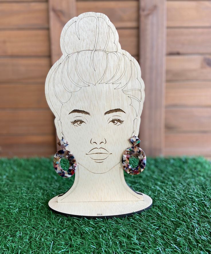 a wooden cutout of a woman's head with earrings on top of it