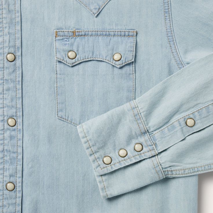 This light blue Western-style shirt is crafted from 100% cotton denim that has been sandblasted for a lived-in look. It has a two point curved back yoke and two point curved pocket flaps with a Stetson “S” embossed on the front left pocket, and “STETSON” embossed on the right sleeve placket. The classic snap front features logo snaps, while the three snap cuff offers a secure fit. Cut with a trim, modern fit for the perfect blend of comfort and style. Light Blue Sandblasted Denim 2 Point Curved Light Wash Chambray Denim Top, Classic Light Wash Denim Top For Spring, Classic Light Wash Long Sleeve Denim Top, Classic Long Sleeve Light Wash Denim Top, Classic Light Wash Denim Top With Button Closure, Classic Light Wash Denim Top With Pockets, Classic Washed Blue Denim Top With Pockets, Classic Medium Wash Chambray Denim Top, Classic Washed Blue Shirt