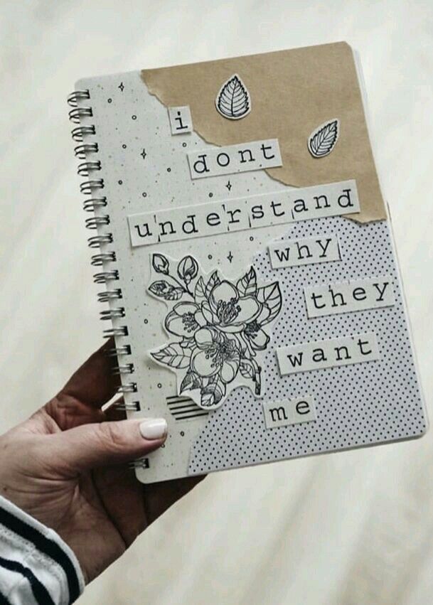 a person holding a notebook with some stickers on it