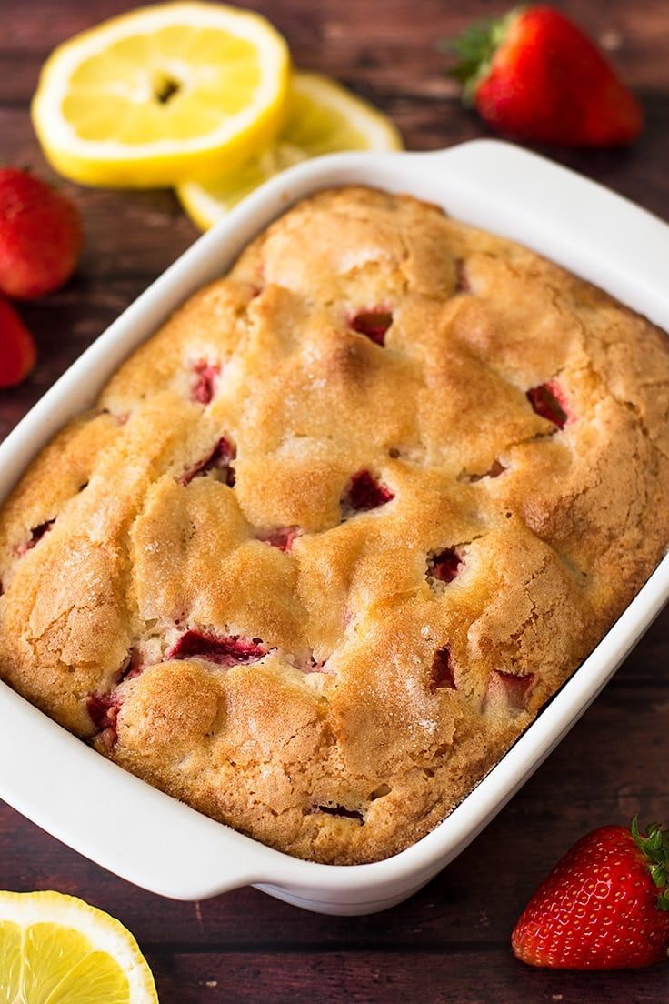 a close up of a cake in a pan with strawberries and lemons around it