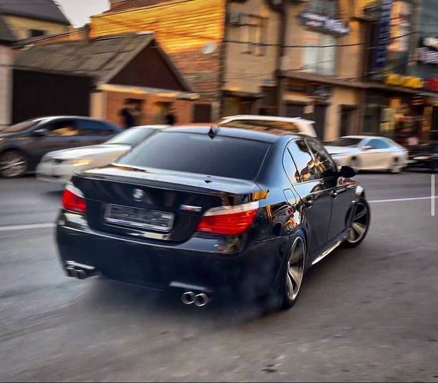 a black car driving down a street next to tall buildings