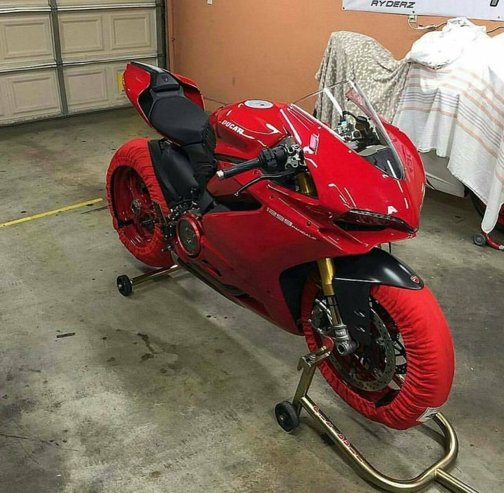 a red motorcycle parked inside of a garage