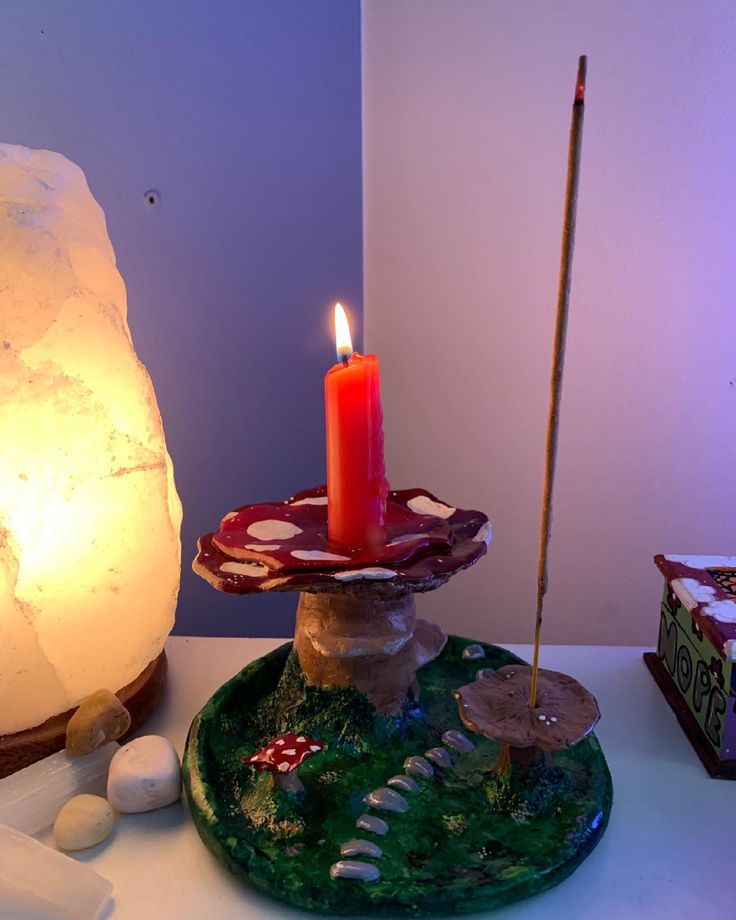 a lit candle is sitting on top of a glass plate with rocks and stones around it